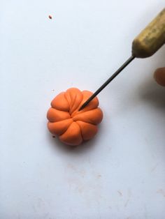 an orange flower is being made with a small metal object and a wooden dowl