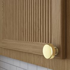 a close up of a door handle on a kitchen cabinet with white tile and wood