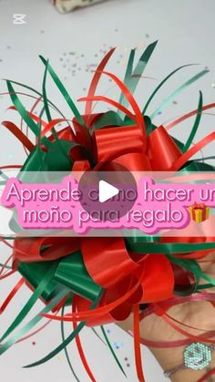 a person holding a red and green bow in their hand with the words aprende no hacer un mono para regallo