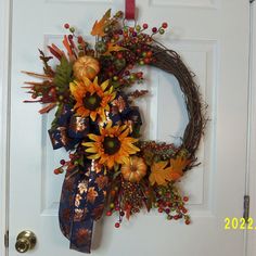 a wreath with sunflowers and berries hangs on the front door