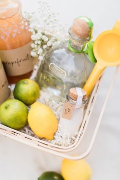 a basket filled with lemons, limes and bottles