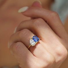 a woman's hand holding a ring with a blue and white stone