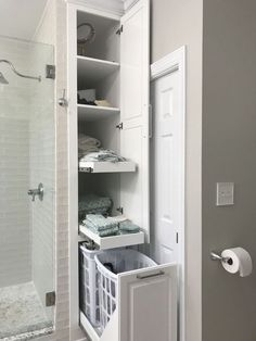 an open door to a walk in shower next to a white cabinet with baskets on it