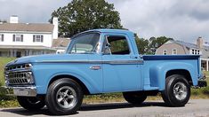 an old blue pickup truck parked in front of a house