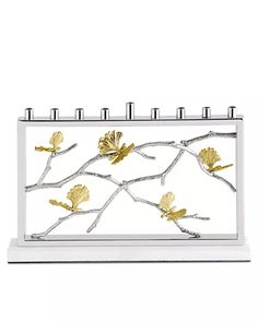 a white and gold desk calendar with flowers on it's front cover, in the shape of a tree branch