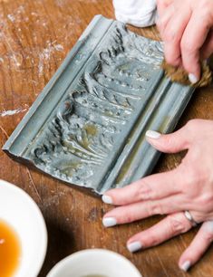 a woman is using a brush to clean an old metal pan with liquid in it