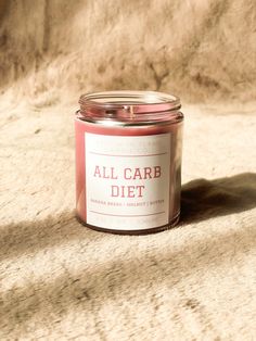 a pink candle sitting on top of a white surface next to a brown cloth covered wall