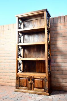 an old wooden bookcase sitting on top of a brick floor next to a wall