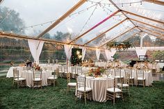 a large tent with tables and chairs set up for a wedding reception in the grass