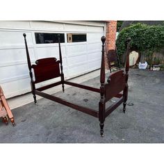 a wooden bed frame sitting in front of a garage