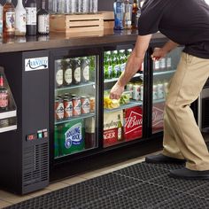 a man standing in front of a refrigeration cooler filled with drinks and beverages