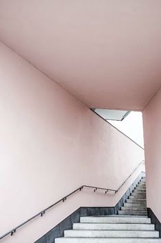 an image of stairs going up the side of a building with pink walls and black railings