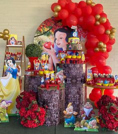 there are many decorations on the table for this birthday party with snow white and red balloons