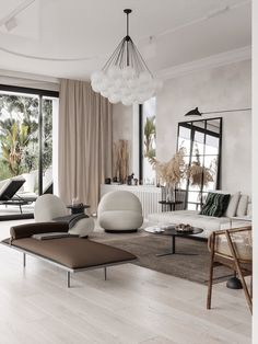 a living room filled with lots of furniture next to large windows and floor to ceiling curtains