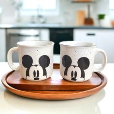 two mickey mouse mugs sitting on top of a wooden tray