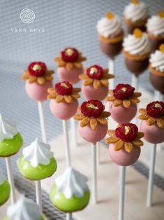 there are many cupcakes on the stick with white frosting and raspberries