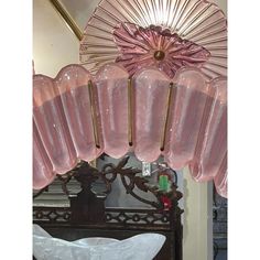 a pink chandelier hanging from the ceiling in front of a mirror and table