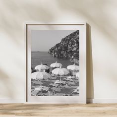 black and white photograph of beach chairs with umbrellas in front of an ocean cliff