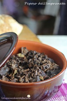 a bowl filled with food sitting on top of a table next to a piece of bread