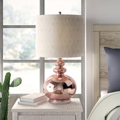 a bedroom with a bed, nightstand and lamp next to a window that has a plant in it