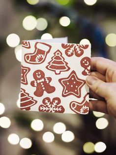 someone holding up a christmas card with gingerbreads and snowflakes on it