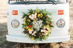 an old vw bus decorated with flowers and greenery