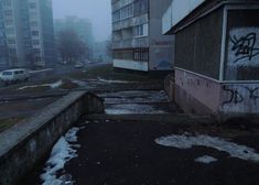 an empty street with graffiti on the side and buildings in the backgrouds