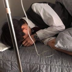 a man laying on top of a bed next to a metal headboard and lamp