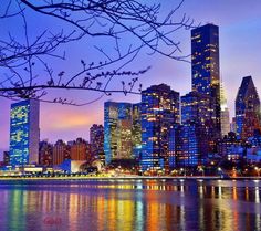 the city is lit up at night and reflecting in the water with its lights on