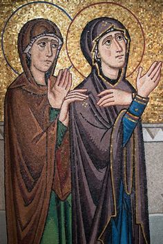 two people standing next to each other in front of a mosaic