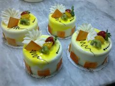 four cakes with fruit on them sitting on a table