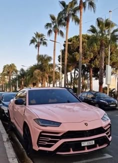 a pink sports car is parked on the side of the road in front of palm trees