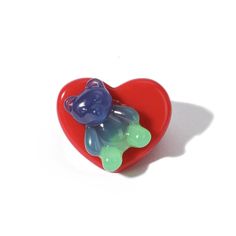 a heart shaped object with a bear on it's back, against a white background