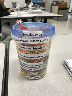 a cup filled with jelly beans sitting on top of a table next to a notebook