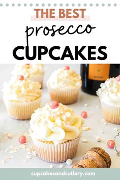 some cupcakes with white frosting and sprinkles on top are next to a bottle of wine