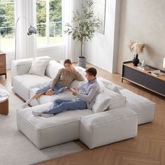 two people sitting on a white couch in a living room