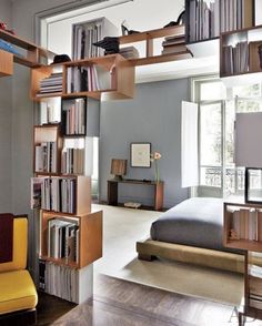 a bed sitting in a bedroom next to a book shelf filled with lots of books