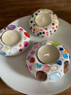 two candles are sitting on a plate decorated with flowers and dots, one has a candle in the middle