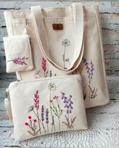 three bags with embroidered flowers on them