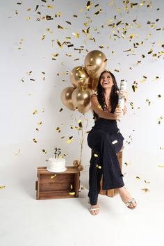 a woman sitting on a chair with balloons and confetti in front of her