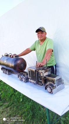 a man standing next to a table with a model truck and tank on top of it