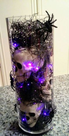 a glass filled with fake skulls and purple light up eyes on top of a counter