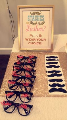 there are many pairs of glasses sitting on the table next to each other, and one has a sign that says staches do lashes?