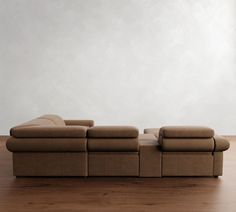 a couch sitting on top of a hard wood floor next to a white wall in an empty room