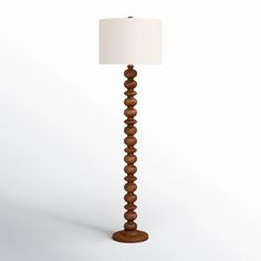 a wooden floor lamp with a white shade on the top and bottom part of it