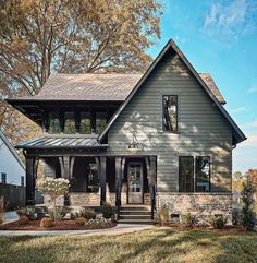 a gray house with black trim and two story windows on the second floor is surrounded by trees