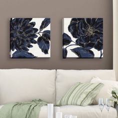 two black and white flowers are hanging on the wall above a couch in a living room