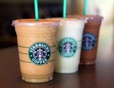 three starbucks drinks sitting next to each other on a table