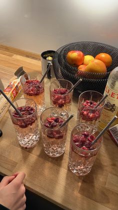 four glasses filled with fruit sitting on top of a wooden table