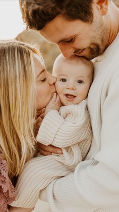 a man and woman holding a baby in their arms